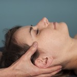 A patient's head rests on the hands of a therapist during a Craniosacral Therapy session.