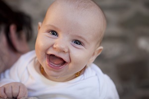 Smiling baby in a white romper.